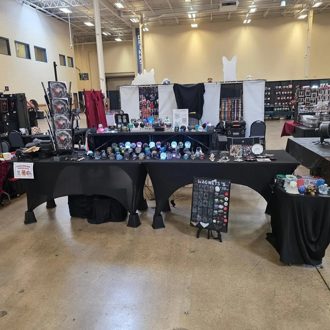 Indoor convention booth with black tablecloths and resin skulls
