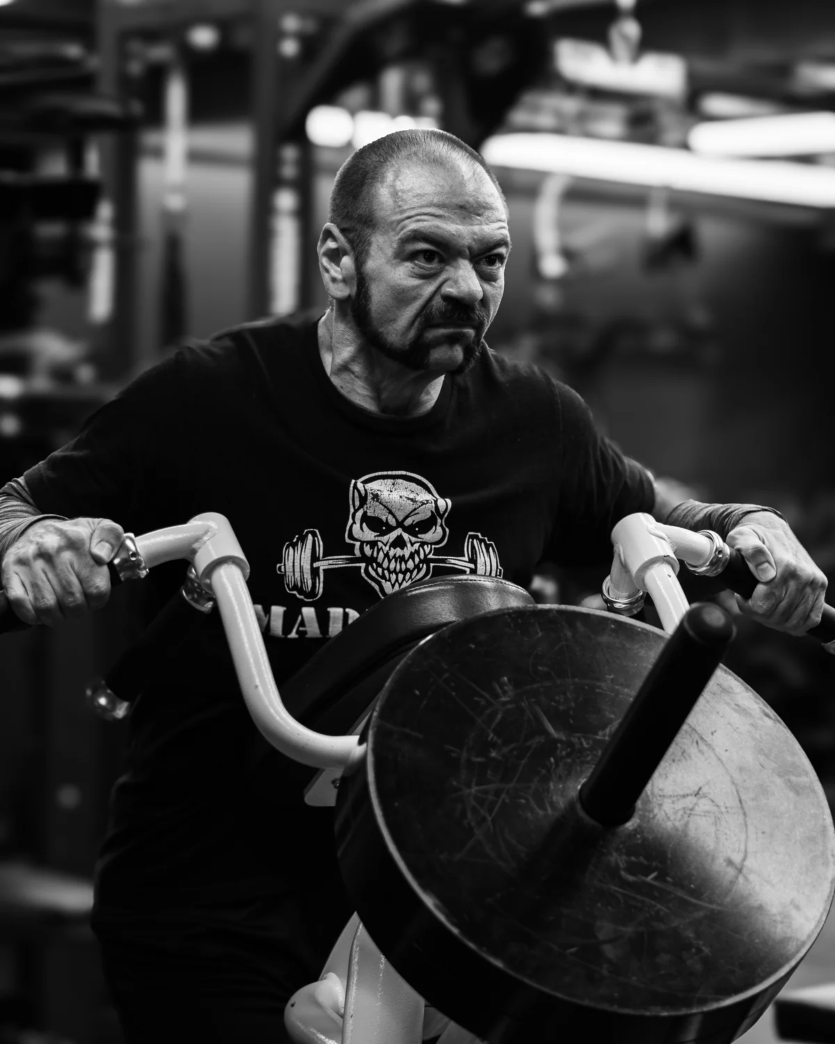 Black and white photo of Dan La Ferlita training in the gym, wearing a skull and barbell t-shirt