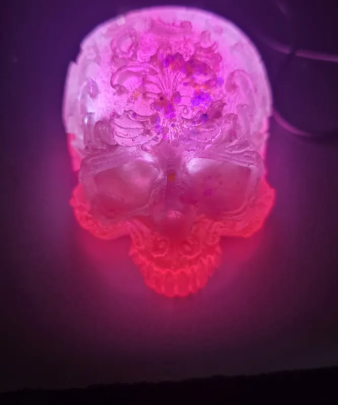 Ornate resin skull lamp glowing pink and red in the dark