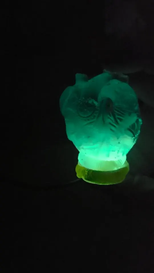 Resin skull lamp glowing green in a dark room