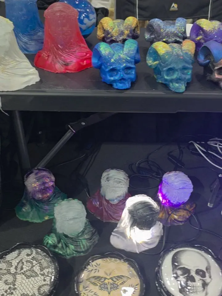 Table of colorful cast resin skulls, some lit from inside